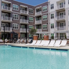 Relax and unwind poolside a building with a pool in front