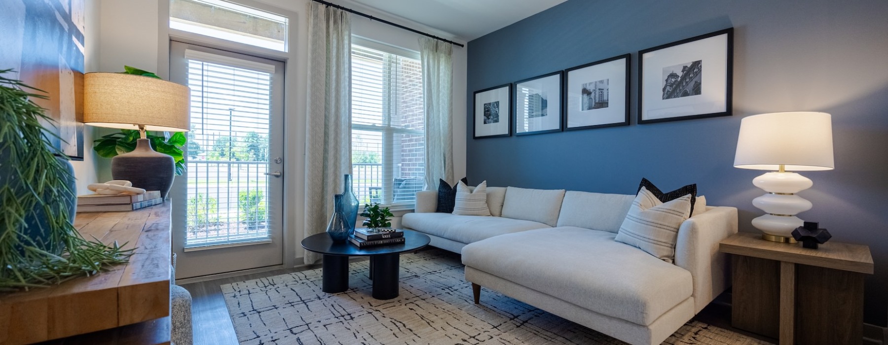 Madison Ironbridge apartment living room with sectional sofa, accent wall, large windows, and patio door.